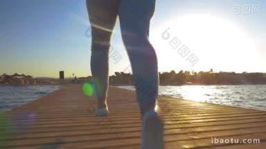慢动作斯坦尼康和低角度拍摄的妇女在度假村的晚上训练，她沿着码头跑步